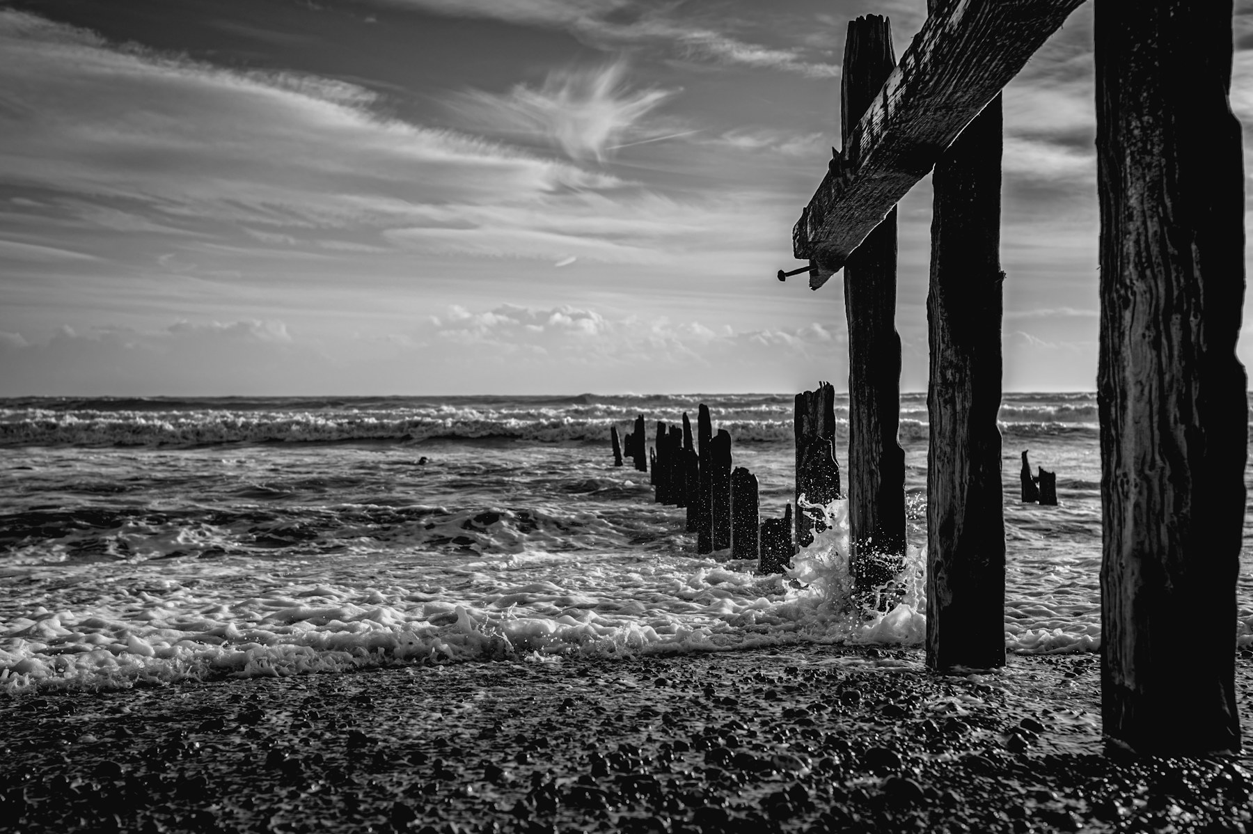Sea washes over timber groynes on a pebble beach