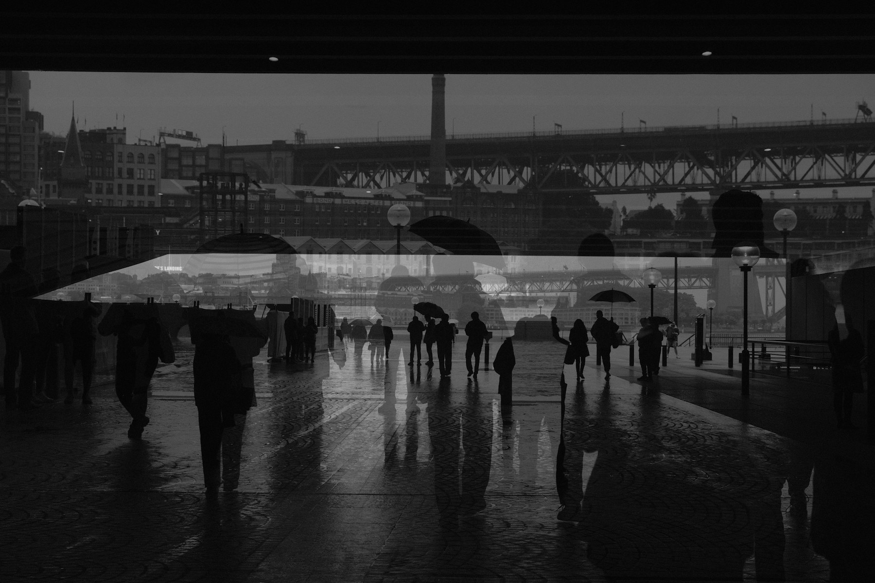 Layered black and white city scene with umbrellas in the rain
